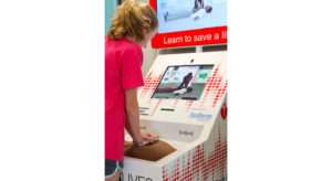 Young girl learning hands-only CPR at the American Heart Association hands-only CPR training kiosk.