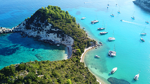 Aerial drone bird's eye view photo of iconic small port and fishing village of Lakka with traditional Ionian architecture and sail boats, Paxos island, Ionian, Greece